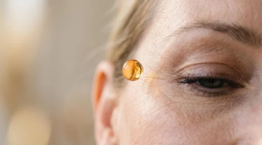 Gros plan artistique sur une goutte de sérum translucide posée sur une peau lisse au niveau du contour de l'œil, évoquant l'action ciblée du CBD sur les rides profondes